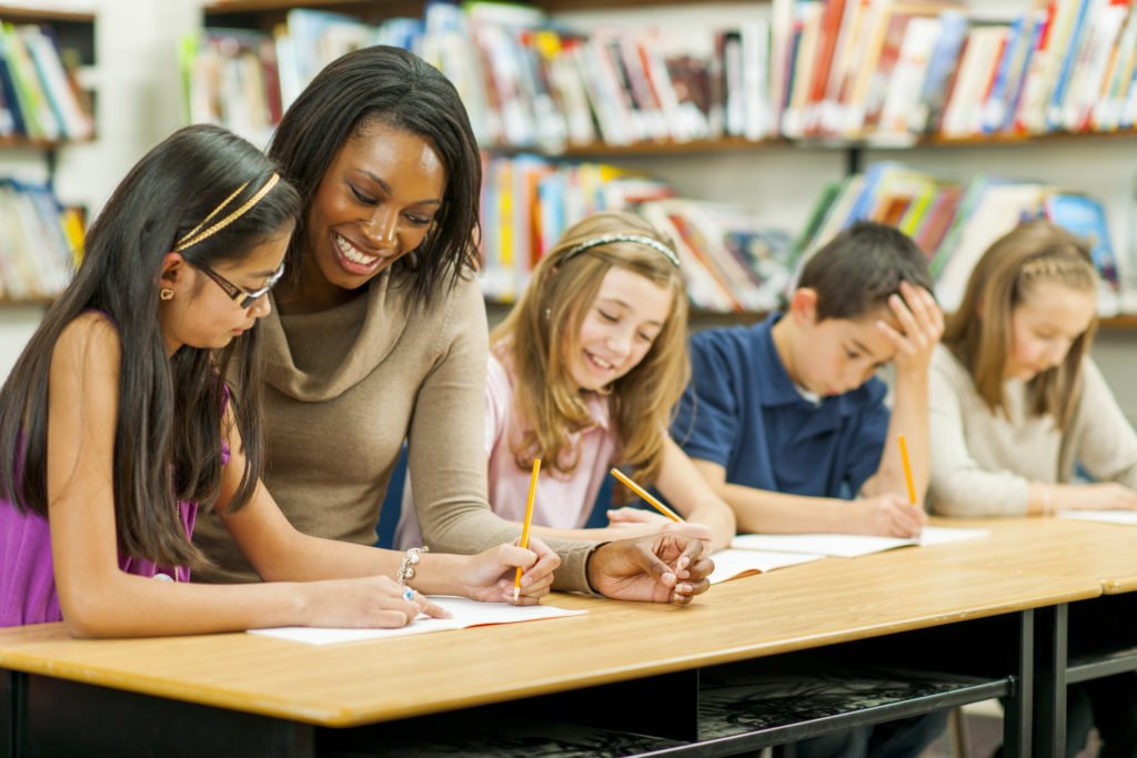 Teacher helping students in classroom - TeacherMade